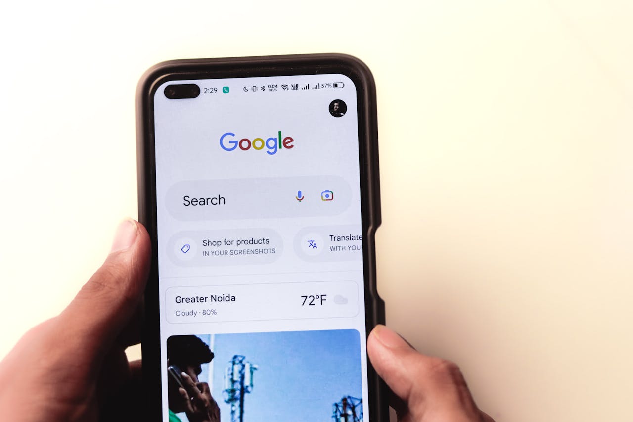 A close-up of a hand holding a smartphone with Google search displayed on the screen.